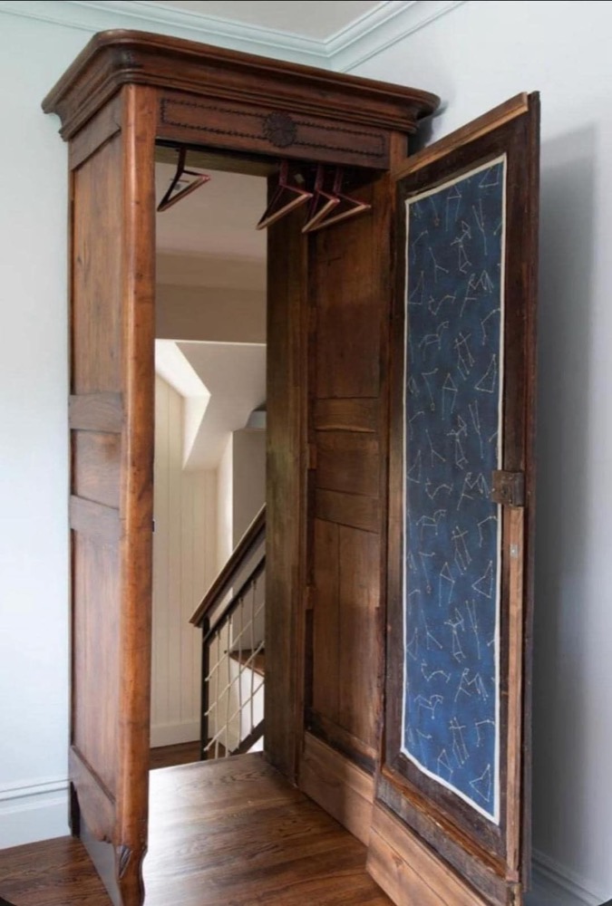 An antique wooden wardrobe with a hand-drawn constellation star map on the inside of its open door